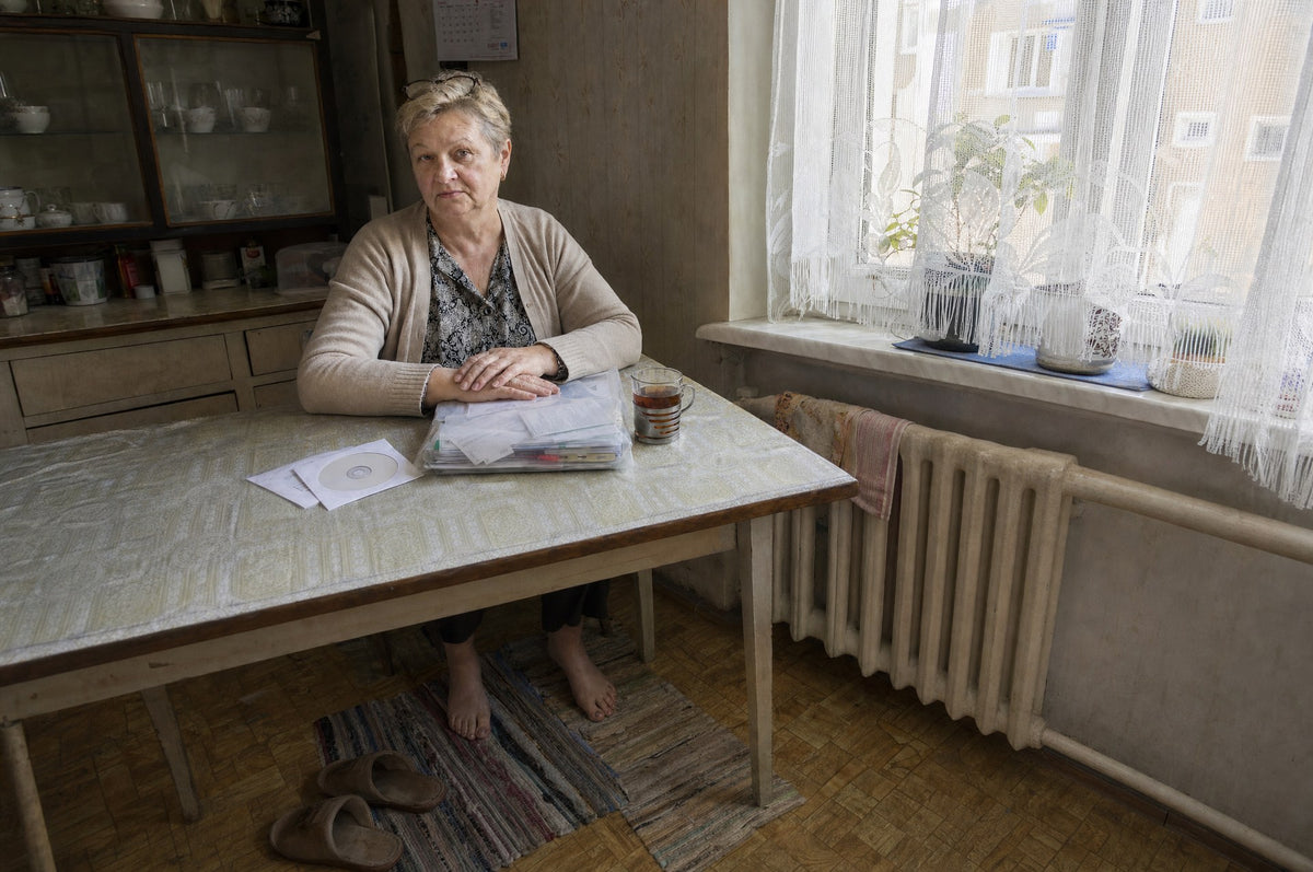 Pani Halina, 64 lata, przy stole w kuchni z teczką wyników badań